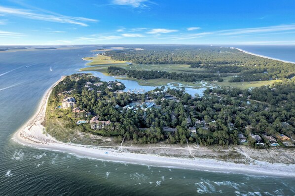 Vista aérea de una zona costera con playa, edificios residenciales y un puerto deportivo.