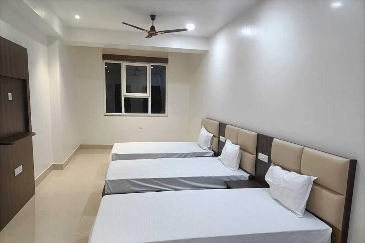 Une chambre d’hôtel avec deux lits, un ventilateur de plafond, une fenêtre et une armoire.