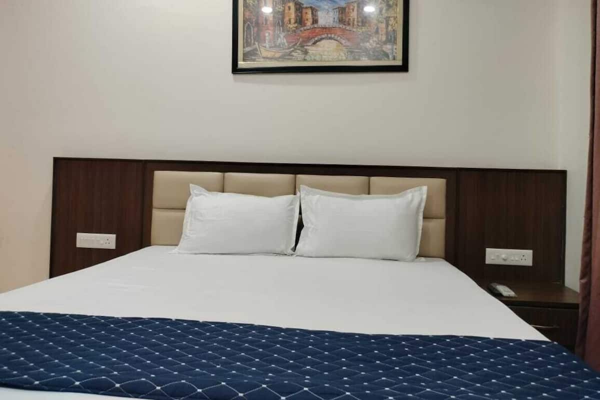 Une chambre d’hôtel avec un grand lit, une tête de lit, un tableau au mur et une table de chevet.