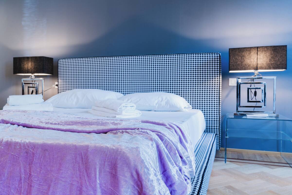 A modern bedroom with a large bed, two bedside tables, and a headboard with a houndstooth pattern.