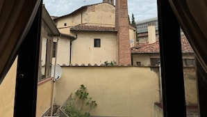 A view through a window of a building with a tiled roof, a chimney, and a small window. - Residenza la Scala (Florence)