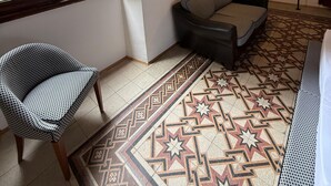 A room with a patterned floor, a sofa, a chair, a standing lamp, and a window with curtains. - Residenza la Scala (Florence)