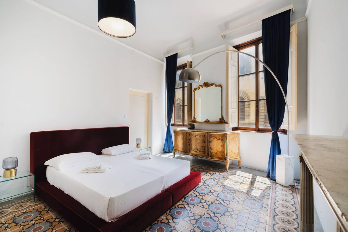 A hotel room with a large bed, a dresser, a mirror, and a window with curtains.