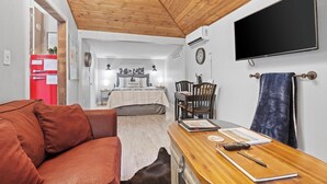 A cozy room with a wooden ceiling, a TV mounted on the wall, a red refrigerator, and a wooden table with a notebook and pen. - Private Hot Tub - 1.4 miles to Main Street - 5 minute drive. (Fredericksburg)