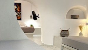 Un intérieur moderne avec un mur blanc incurvé, un canapé, une petite table ornée de fleurs et un panier.