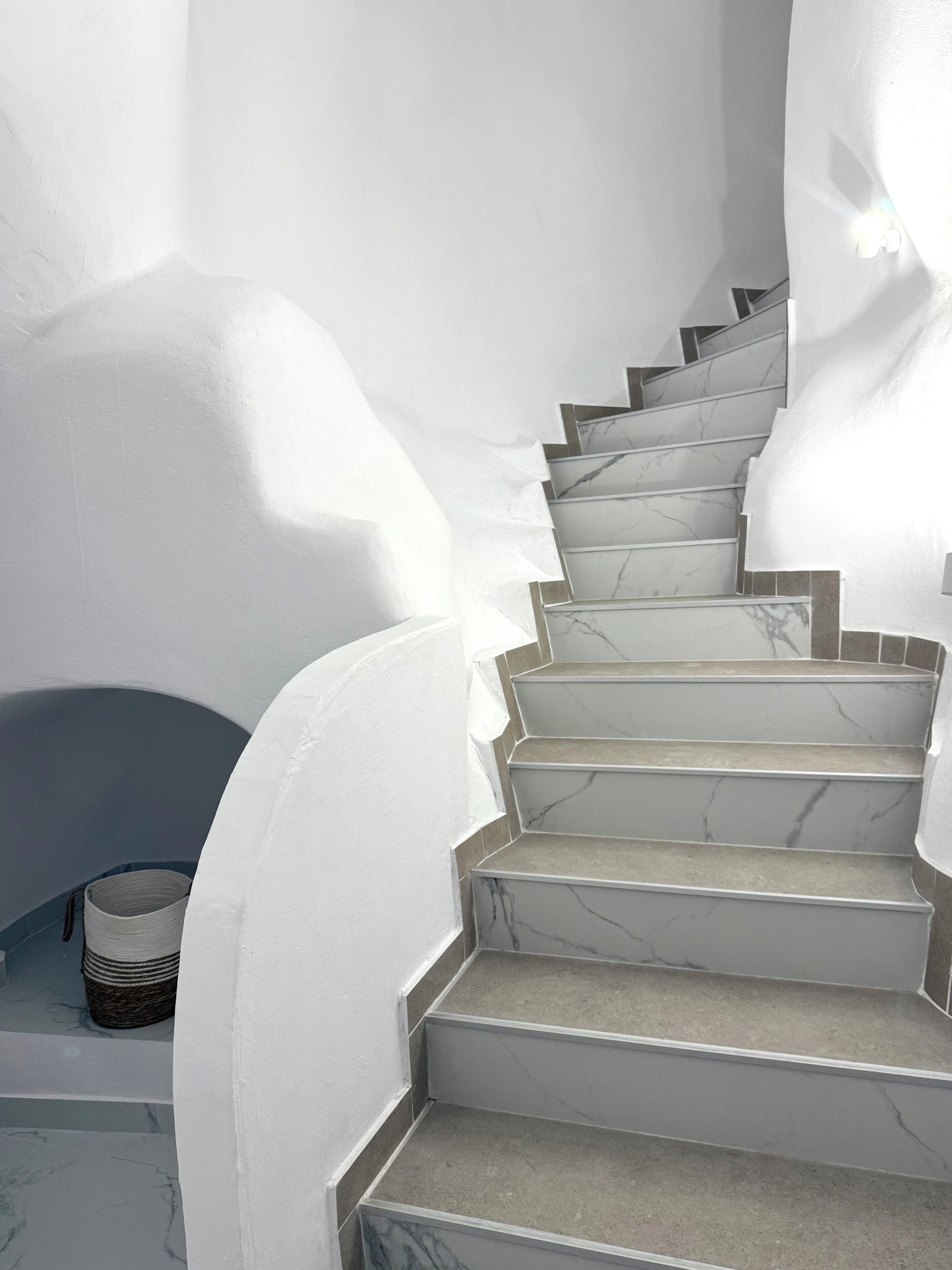A staircase with white walls and marble steps.