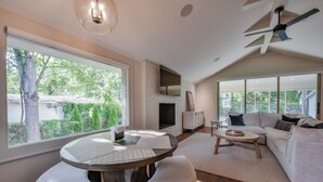 Una sala de estar moderna con chimenea, un ventanal grande y un ventilador de techo.