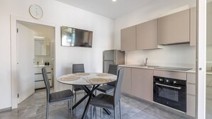 A modern kitchen with a round dining table, grey chairs, a built-in oven, and a large mirror. - Sole Apartment 1 - Central Marina With Modern Furnishings (Ugento)