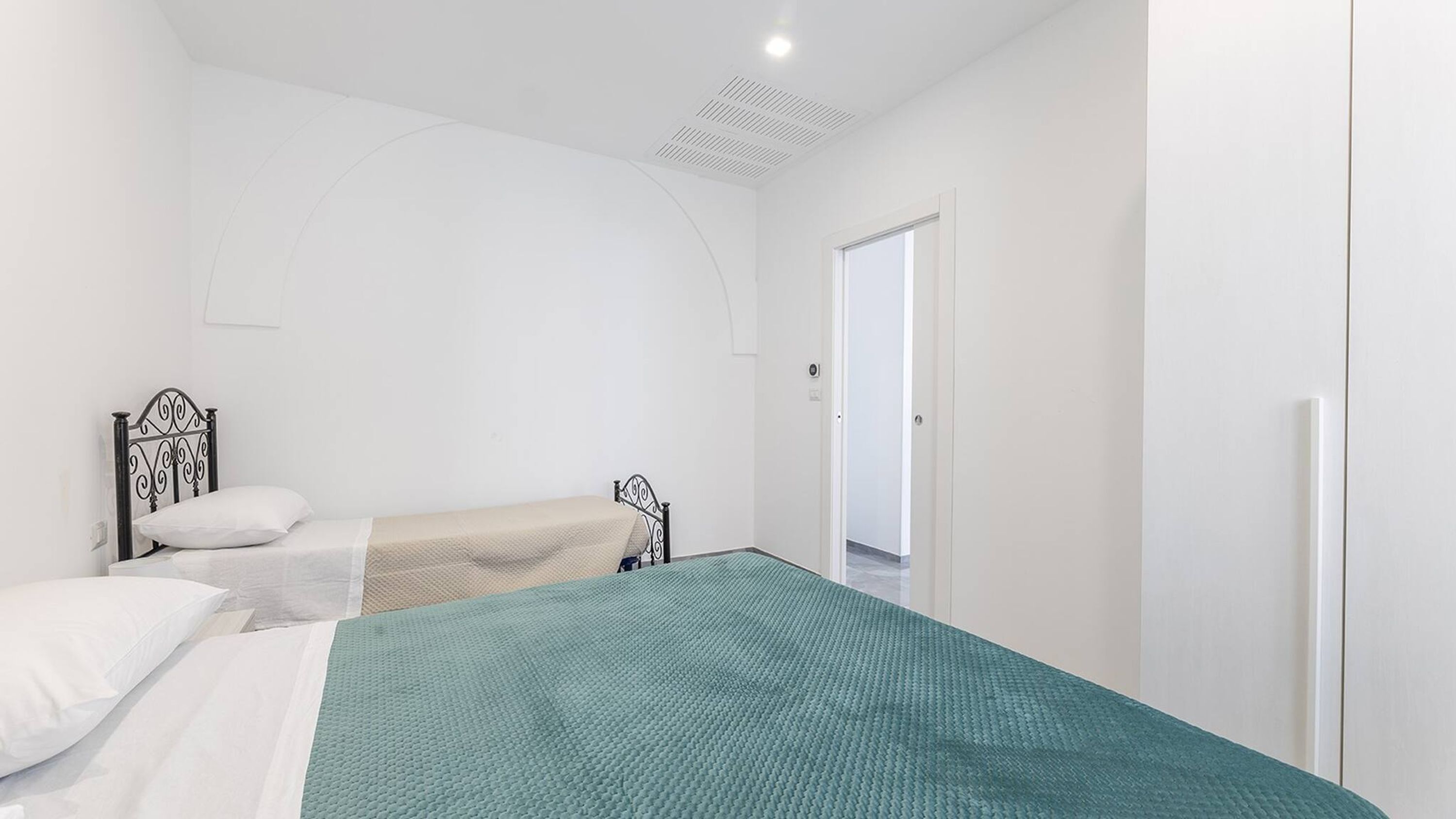 A bedroom with a single bed, a smaller bed, and a wardrobe.
