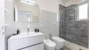 A modern bathroom with a white vanity, a bidet, a glass-enclosed shower, and a large mirror. - Sole Apartment 1 - Central Marina With Modern Furnishings (Ugento)