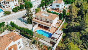 A modern villa with a swimming pool, multiple balconies, and a landscaped garden.