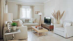 A modern living room with a sofa, a coffee table, a TV, and decorative plants.