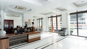 A modern reception area with a wooden desk, several computers, and a seating area with a sofa and chairs.