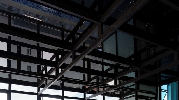 An indoor swimming pool with clear blue water, large windows, and a city view.