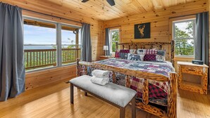 Un dormitorio de cabaña de madera con una cama grande, un banco y un ventilador de techo.