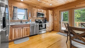Cocina de cabaña de madera con refrigerador, microondas, horno y lavavajillas de acero inoxidable.