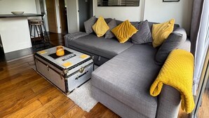 A modern living room with a grey sectional sofa, a small coffee table, and a wooden floor. - Beautiful Snowdonia Tree Top View Chalet in North Wales (Caeathro)