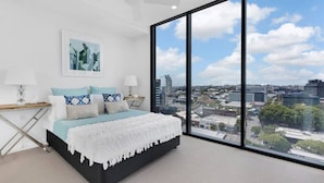 Un dormitorio moderno con una cama grande, vistas de la ciudad y un ventilador de techo.