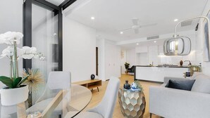 Una sala de estar moderna con una mesa de comedor de vidrio, sofás grises y una mesita decorativa.
