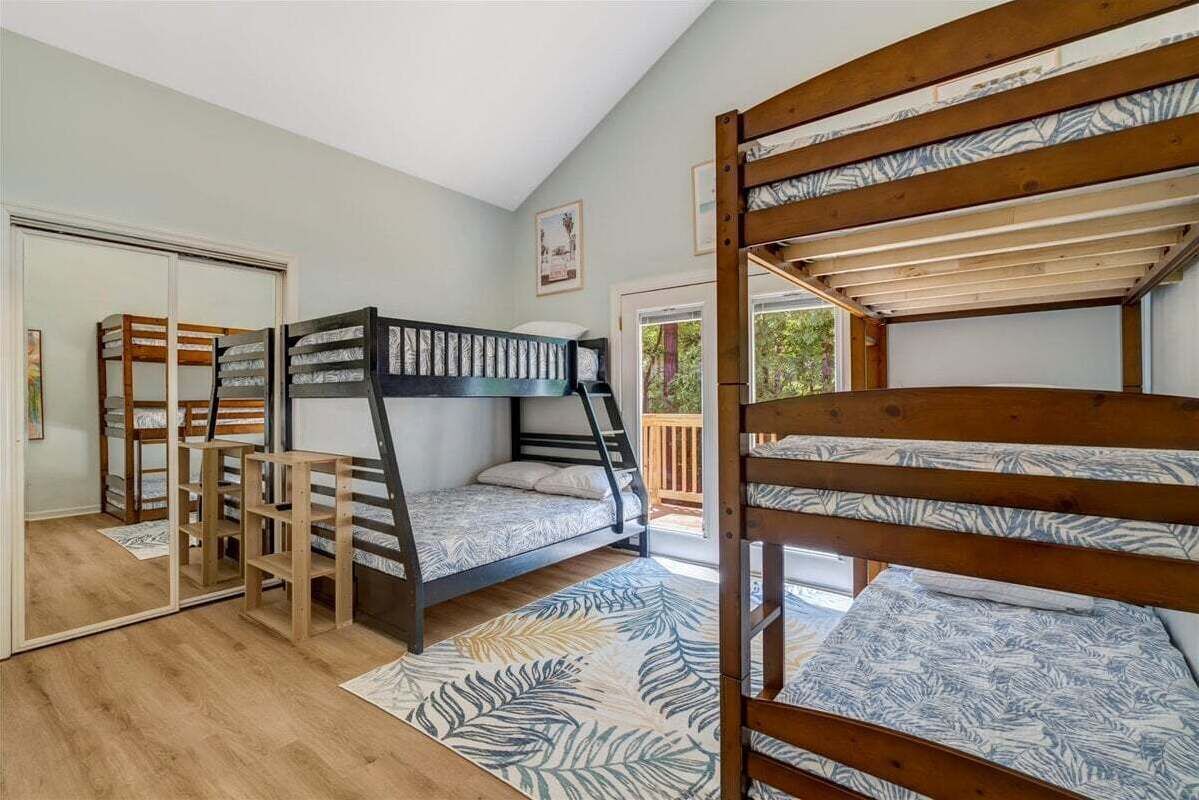 Ein Zimmer mit Etagenbetten, einem Spiegel, Holzboden und einem gemusterten Teppich.