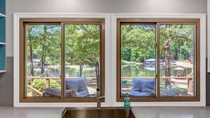 A kitchen with a large window overlooking a backyard with a pond and outdoor seating. - The Greatest Cove, Man! | Spectacular Panoramic Playground (Henrico)