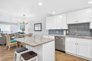 A modern kitchen with white cabinets, a granite countertop, and a built-in dishwasher.