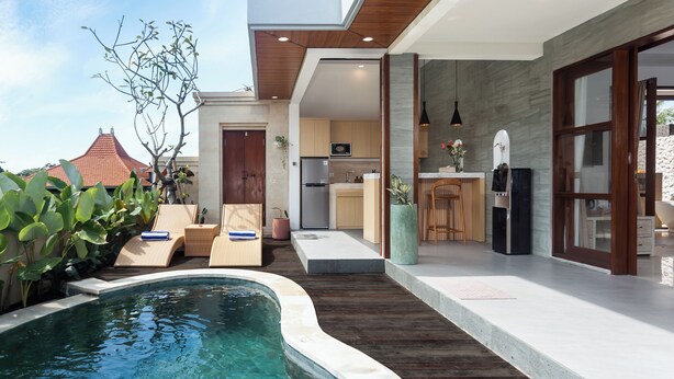 A modern outdoor pool area with lounge chairs, a kitchen, and a dining area. - Green Kulu Villa (Tampaksiring)