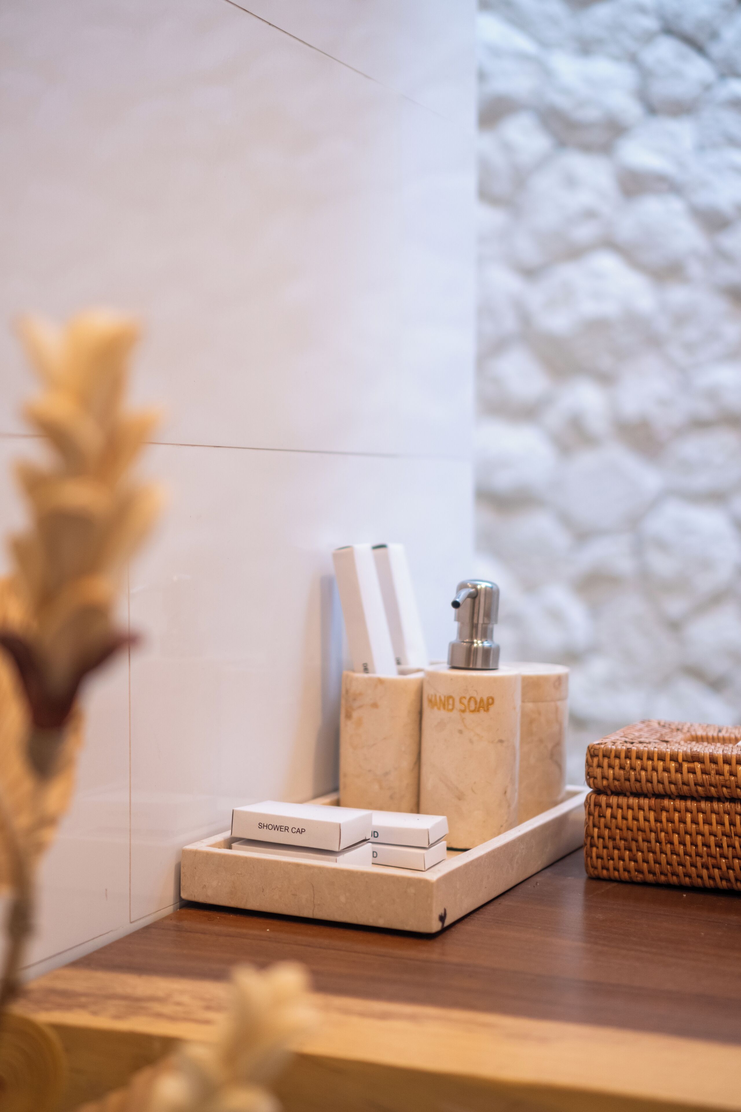 A bathroom vanity with a marble countertop, a shower cap, and a hand soap dispenser.