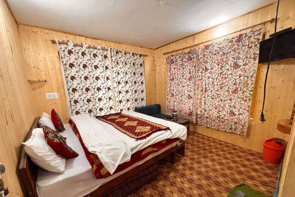 A room with a bed, curtains, a small table, and a chair.