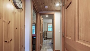 Puinen käytävä, jonka vasemmalla puolella on kello. Käytävä johtaa huoneeseen, jossa on ikkuna ja patteri.