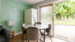 Un comedor con mesa y sillas, un armario y vistas de un jardín a través de una puerta corredera.