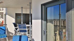 A balcony with a table and chairs, a sliding glass door, and a view of buildings.