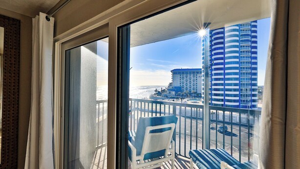 A balcony with a view of a beach and a tall hotel building.
