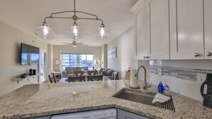 A kitchen with granite countertops, a built-in dishwasher, and white cabinetry.