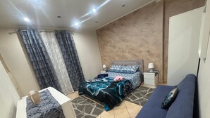 A bedroom with a bed, bedside tables, a sofa, and a patterned rug.