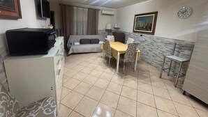 A compact living space with a sofa, a dining table with chairs, a TV, and a microwave.