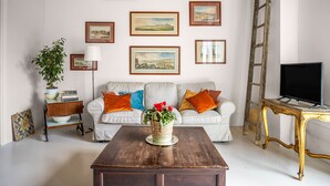 A living room with a white sofa, orange cushions, a wooden coffee table, and a TV on a stand. - Elfranch - El.Chi.Ma. by Wonderful Italy (Polizzi Generosa)