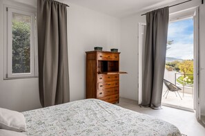 Une chambre à coucher avec un lit, une commode en bois et un balcon avec une chaise.