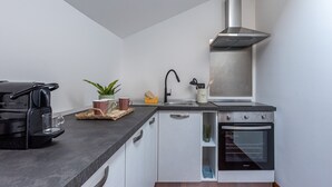 A compact kitchen with a built-in oven, a stainless steel range hood, and a modern countertop. - Kadì Apartment by Wonderful Italy (Palermo)