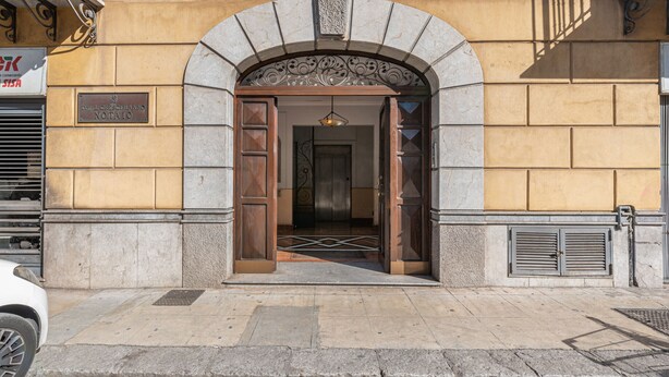 A building entrance with a stone archway, a wooden door, and a metal gate. - Kadì Apartment by Wonderful Italy (Palermo)