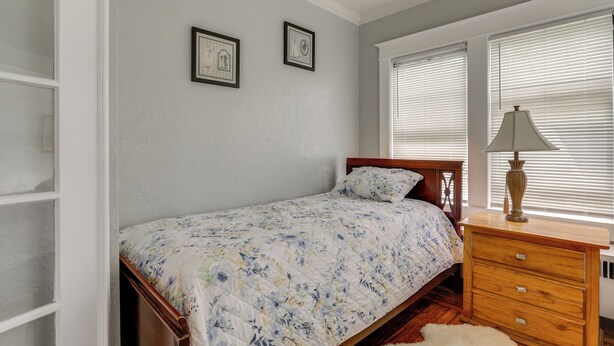 Un dormitorio con cama, cómoda de madera y dos cuadros en la pared.