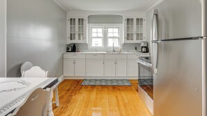 Una cocina con armarios blancos, un refrigerador de acero inoxidable y una ventana sobre el fregadero.
