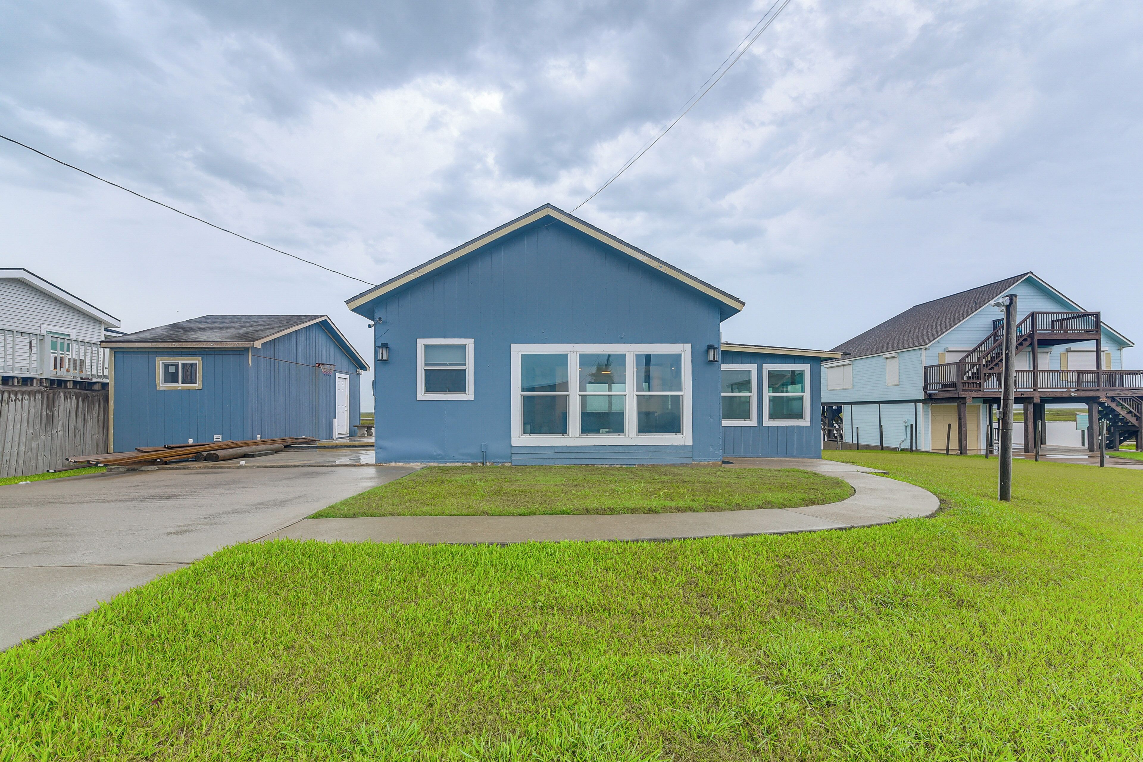 A residential house with a blue exterior, a front yard, and a driveway.
