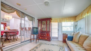 A living room with a sofa, a television, a wooden cabinet, and a dining area with a table and chairs. - < 3 Mi to Hard Rock Stadium: Miami Home w/ Sunroom (Miami Gardens)