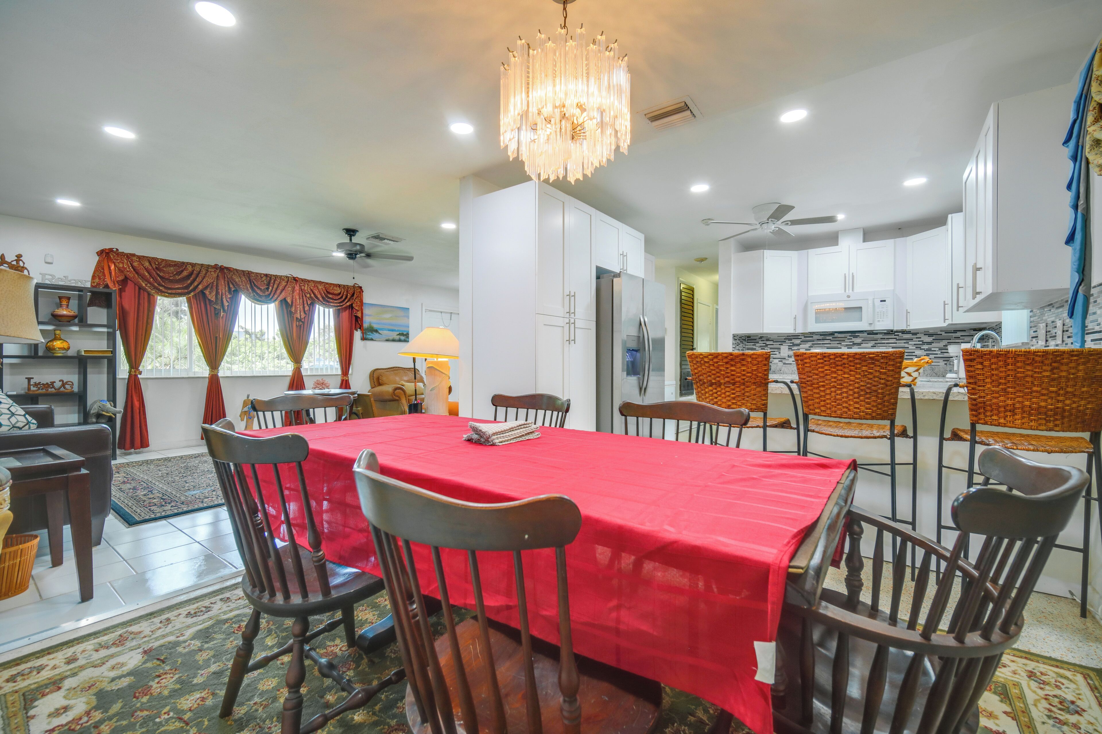 Un coin repas avec une nappe rouge, des chaises en bois et un lustre.
