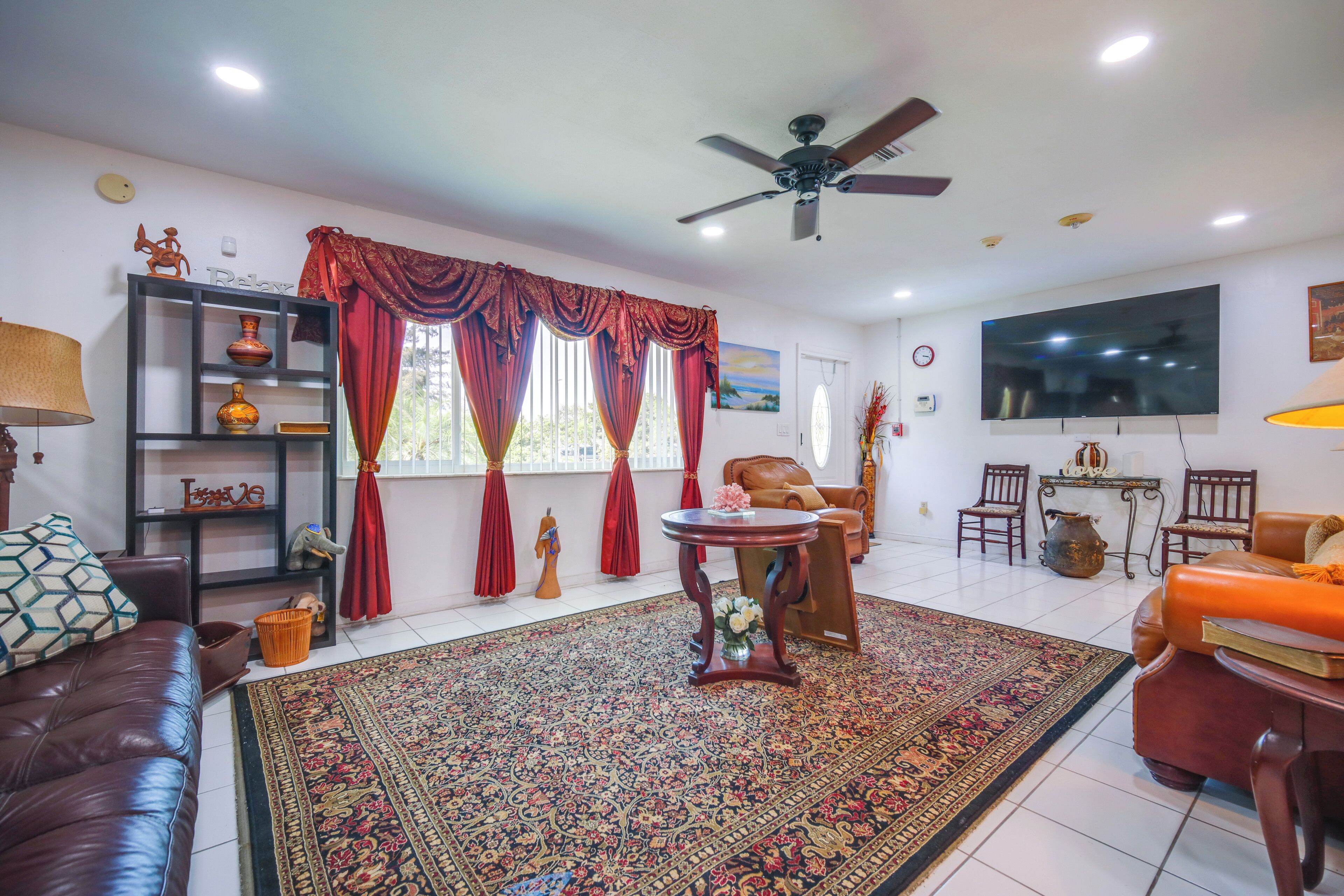 A living room with a sofa, a coffee table, a TV, and a ceiling fan.