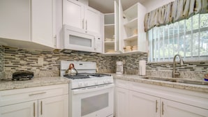 A kitchen with white cabinets, a microwave, a stove, and a sink. - < 3 Mi to Hard Rock Stadium: Miami Home w/ Sunroom (Miami Gardens)