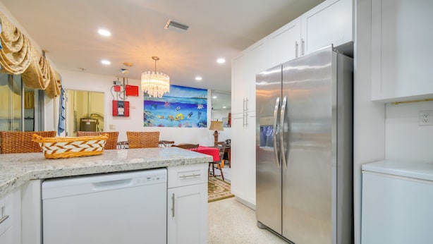 A modern kitchen with white cabinetry, a stainless steel refrigerator, and a decorative wall mural. - < 3 Mi to Hard Rock Stadium: Miami Home w/ Sunroom (Miami Gardens)