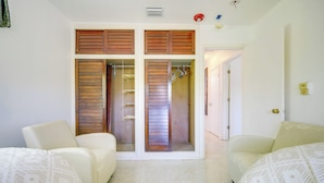A room with two beds, a closet with wooden shutters, and a door leading to another room. - < 3 Mi to Hard Rock Stadium: Miami Home w/ Sunroom (Miami Gardens)