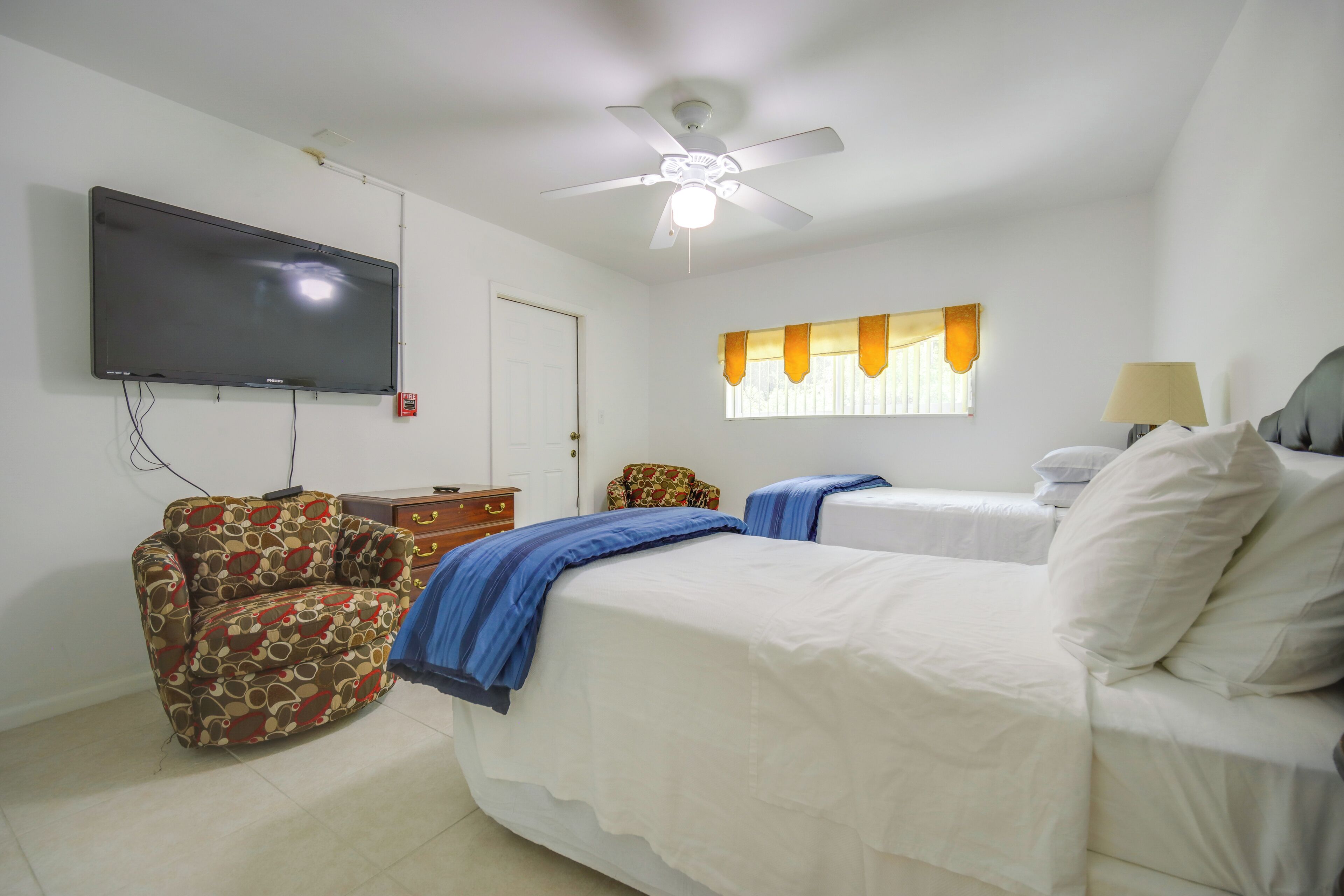 Une chambre à coucher avec un lit, un canapé, une télévision et un ventilateur de plafond.